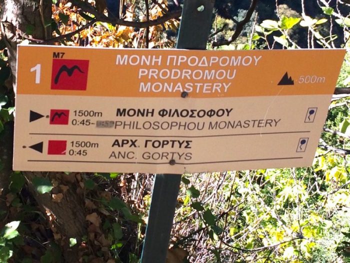 A sign in the lousios gorge showing Philosophou monastery is another 45 minutes and ancient Gortys is 45 minutes in the other direction