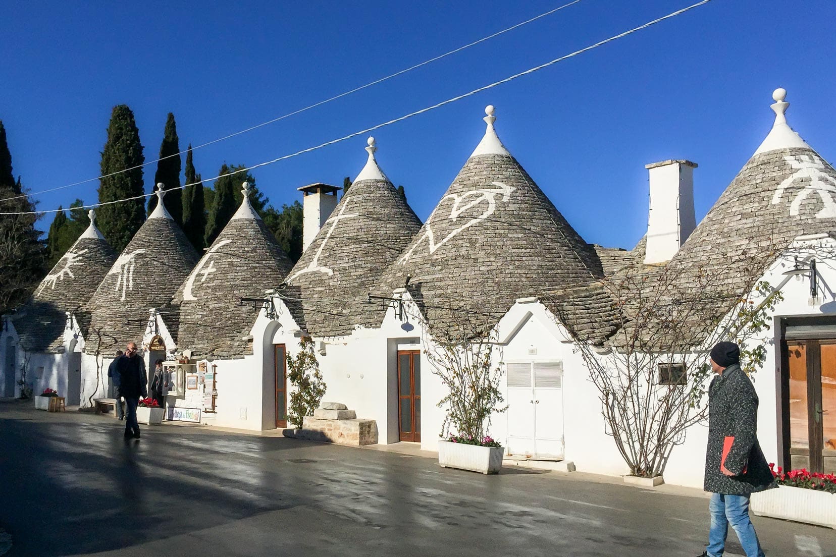 Row of Alberobello trulli with white painted symbols on the roof