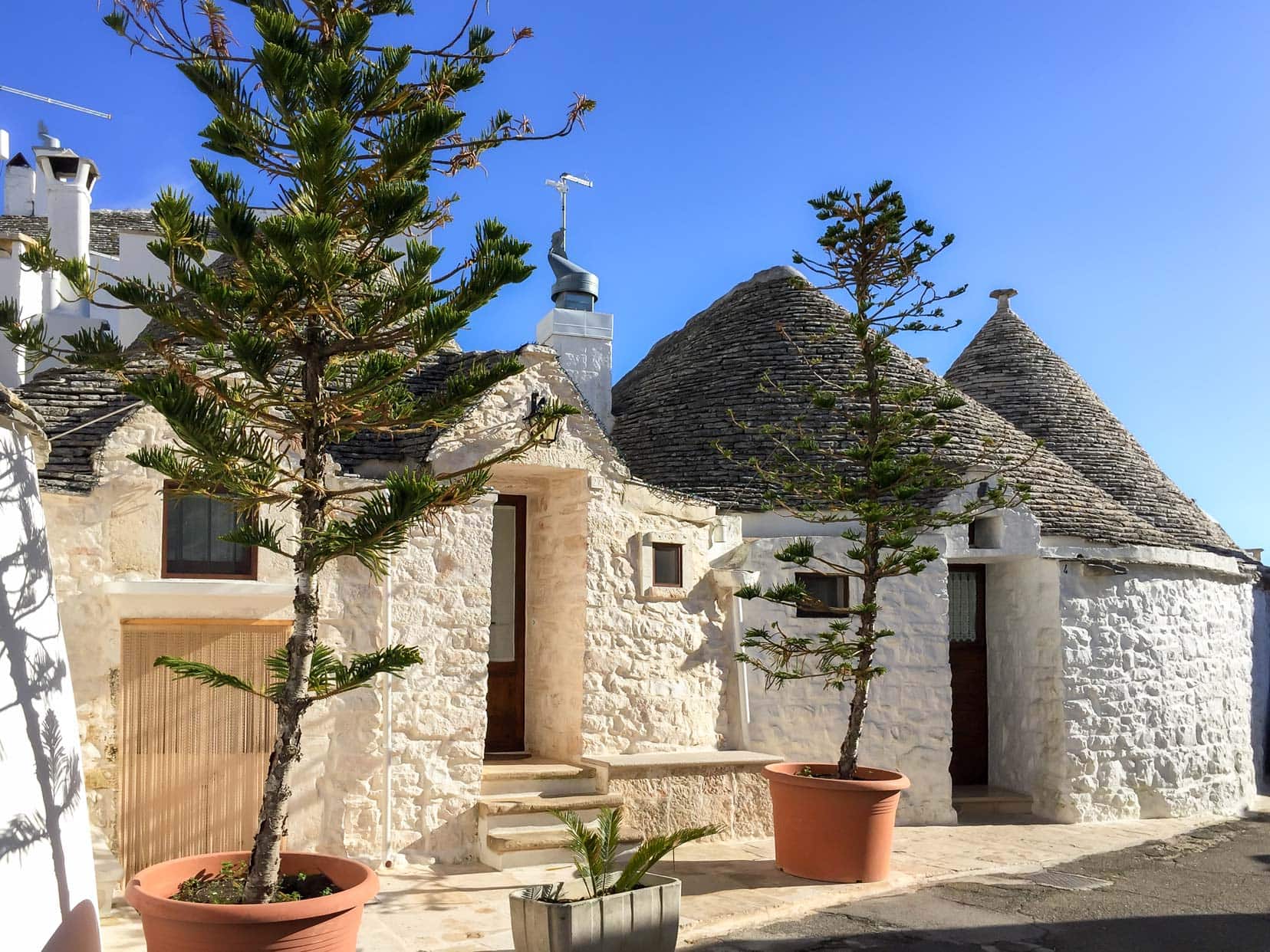 Trulli with pot planted trees outside 