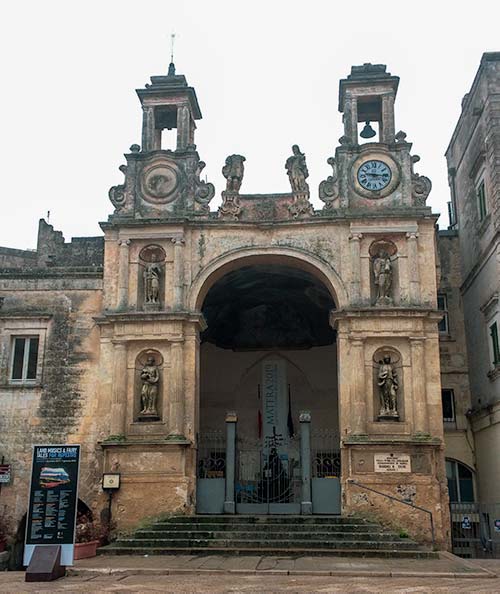 an arch way in Matera with a clock tower as one pillar