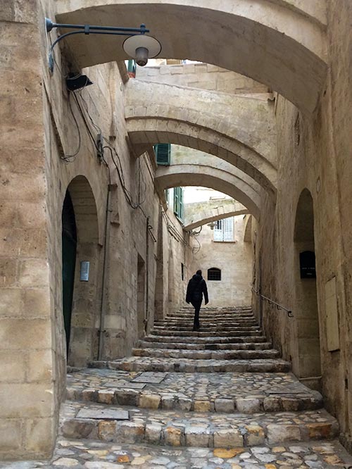 person walking up stone steps with walkways crossing overhead