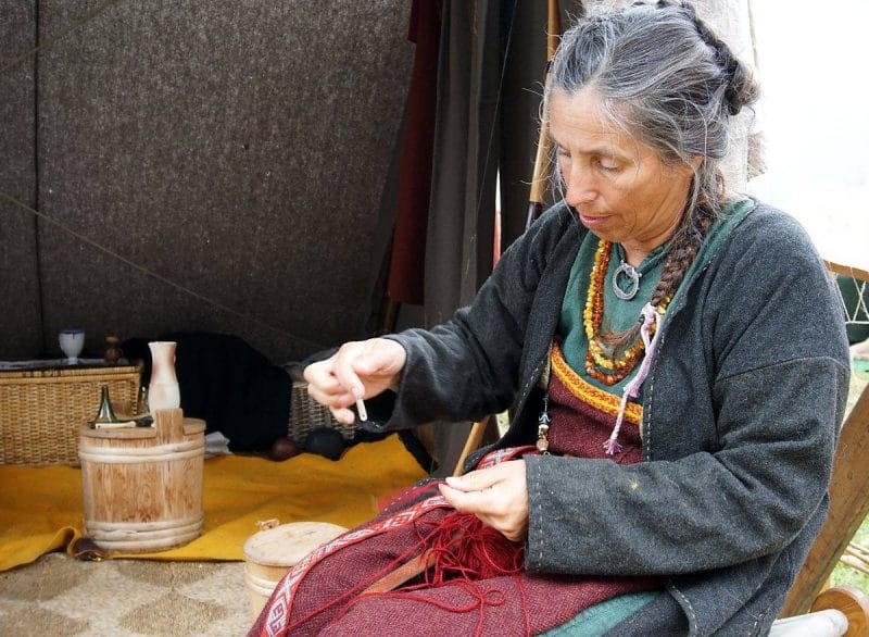 A woman dressed as a viking spinning yarn