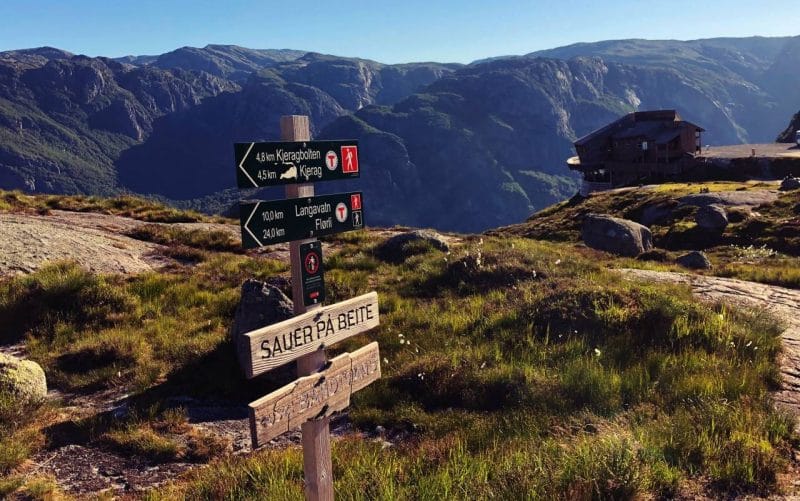 a wooden sign showing the direction to kjeragbolten is 3.5km. Mountains in the background. 