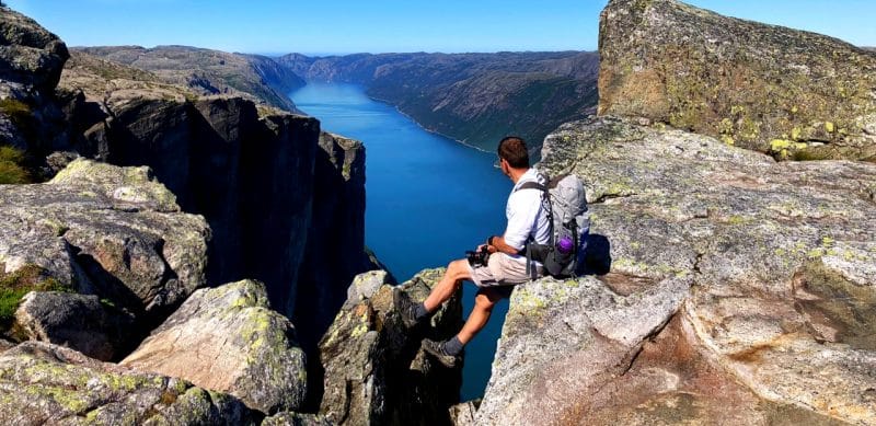 Man looking across a fjord from the mountain above