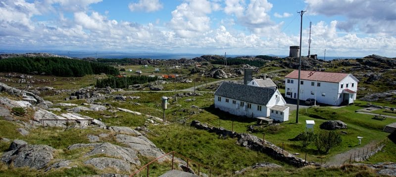 view across Utsira from the top of the lighthouse - can see two buildings and an expansion of green areas with rocks. 