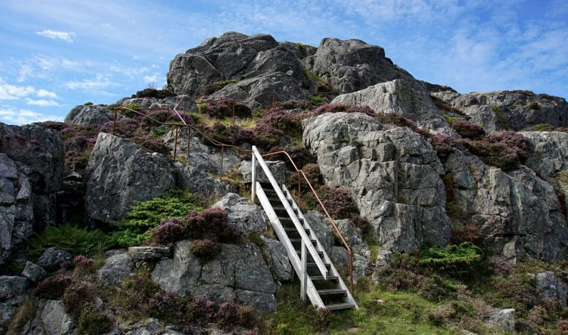 A clump of rock with a wooden staircase leading up the side of the rock.