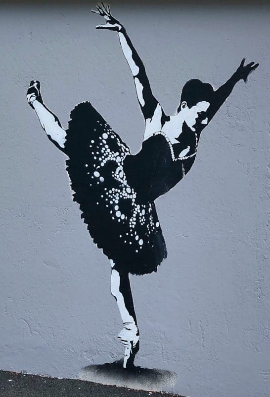 Street art of a black and white ballerina on the side of a house
