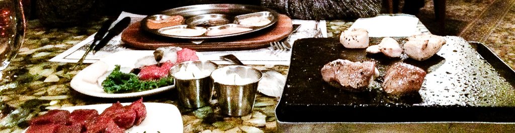 a table in Grizzly House Restaurant in Banff with a hotplate cooking meat and a round platter with various coloured sauces