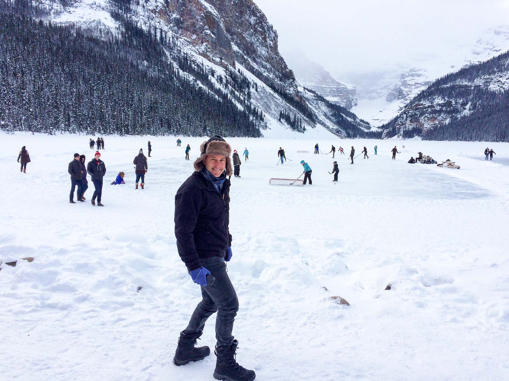 Christmas-in-Banff-Lake-Louise- Lars by the frozen lake with people playing hockey 