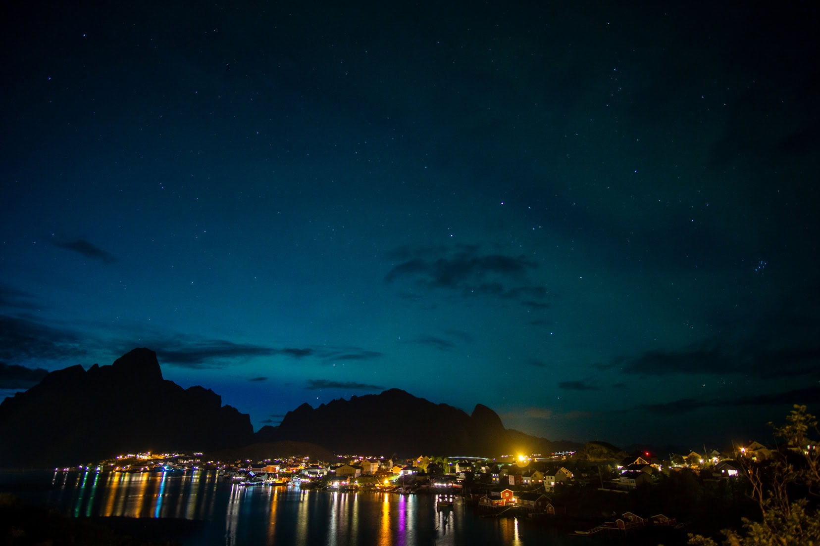 reine-twilight with coloured lights from the houses reflecting on the water 