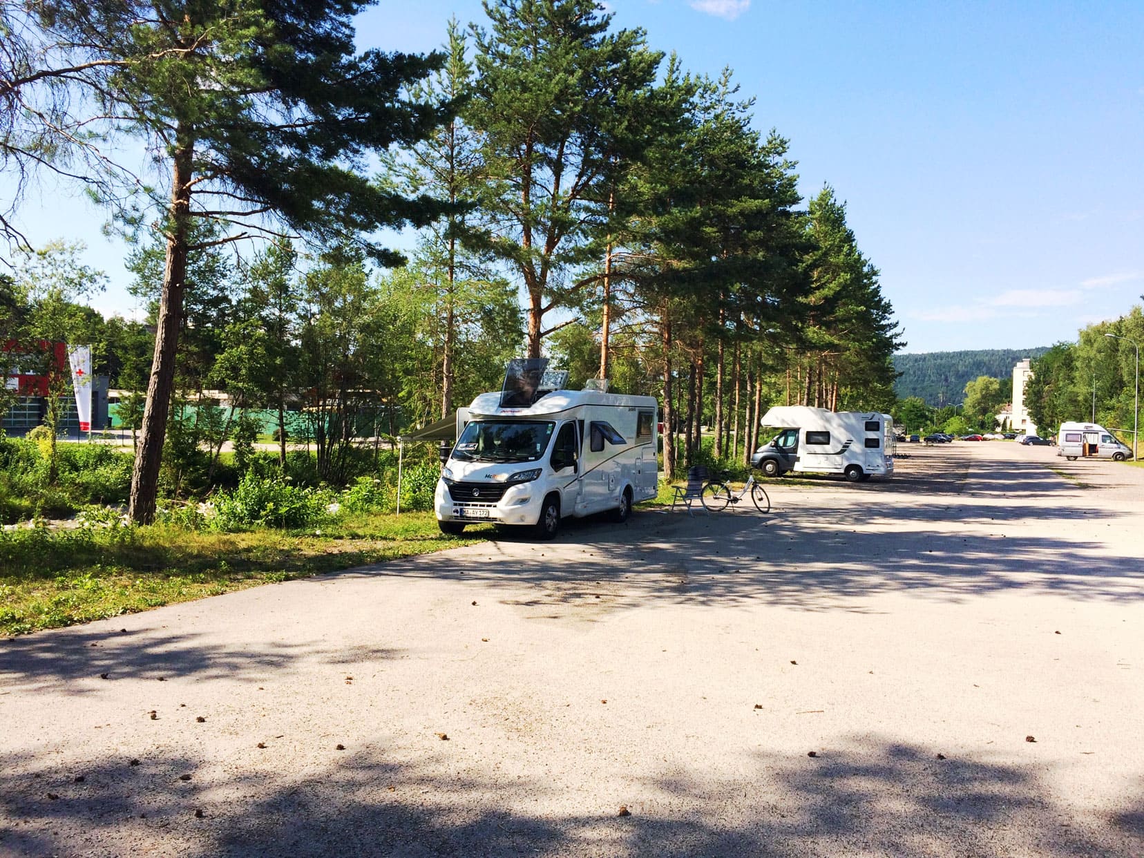 Motorhome parked in large carpark with shady trees