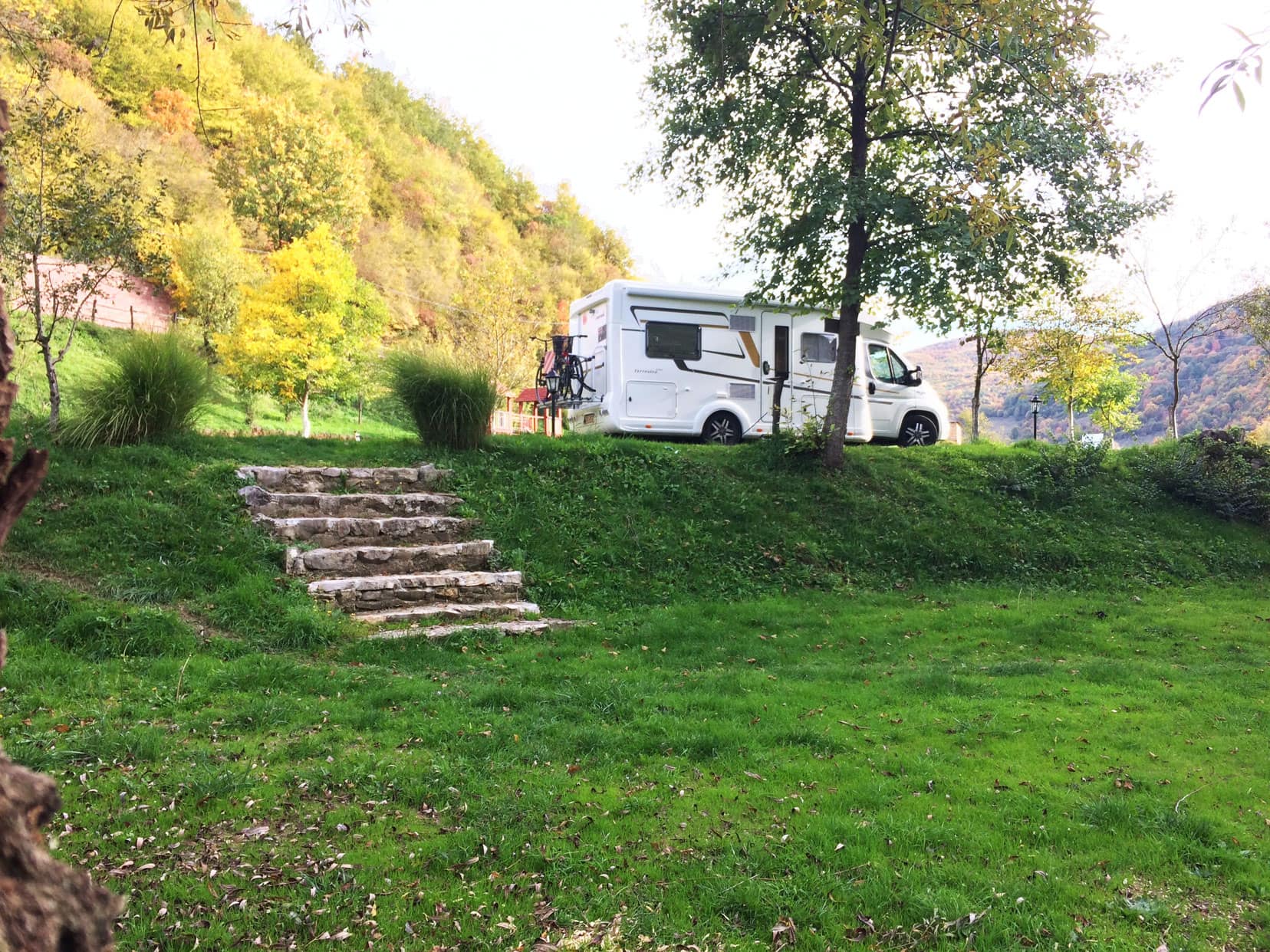Motorhome parked by green field and stone steps