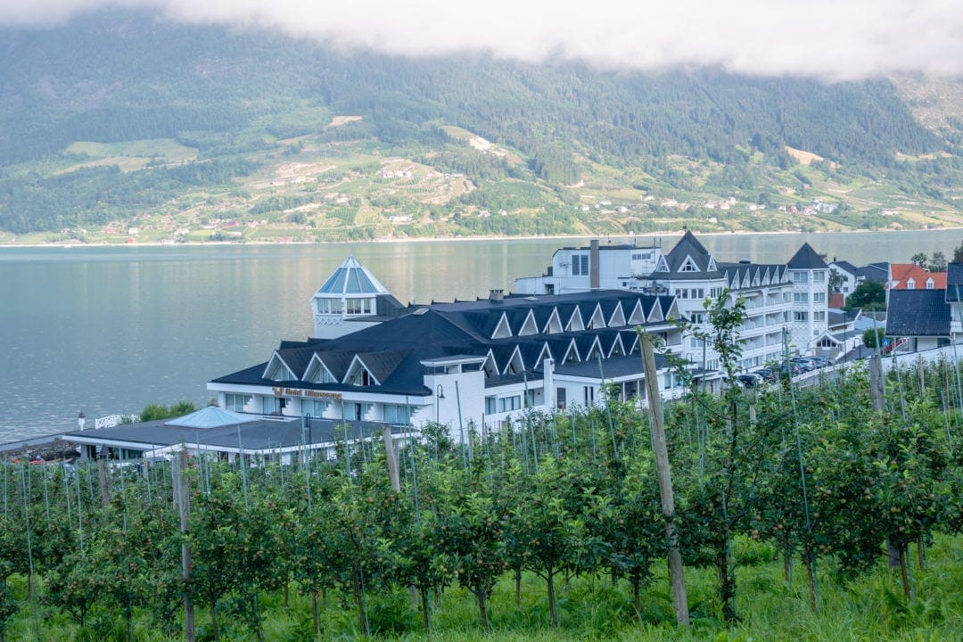 white painted hotel overlooking a fjord with mountain backdrop