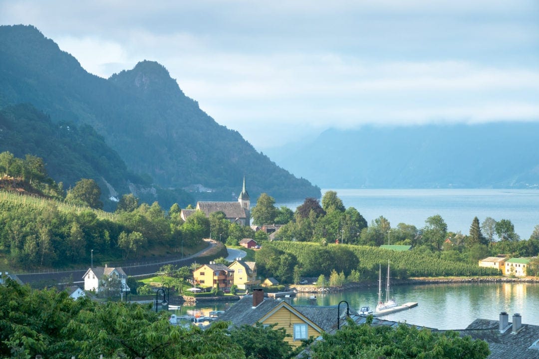 Views down over a town by a fjord with a foggy mountain backdrop