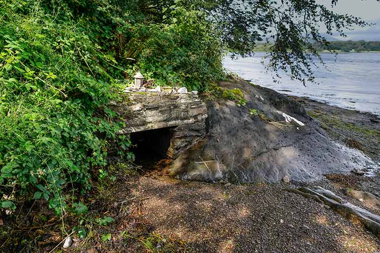 Small stone shelter covering a bubbling underground spring close by the river