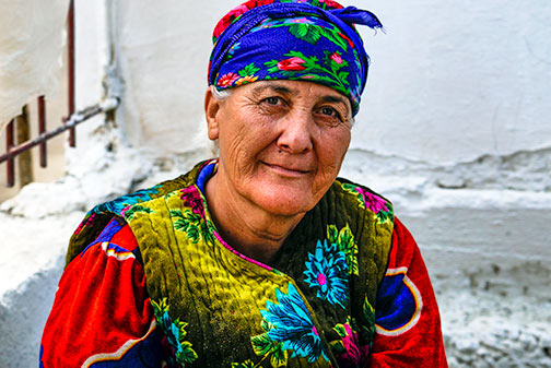 Uzbek local lady dressed in colourful clothes and half-smiling 