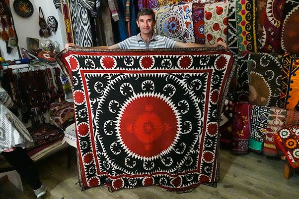 Owner of a textile shop holding a persian carpet in front of him