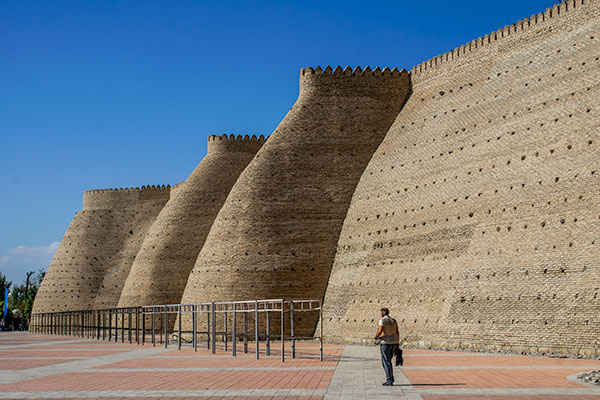 Huge earthen walls of a citadel tower over passers-by