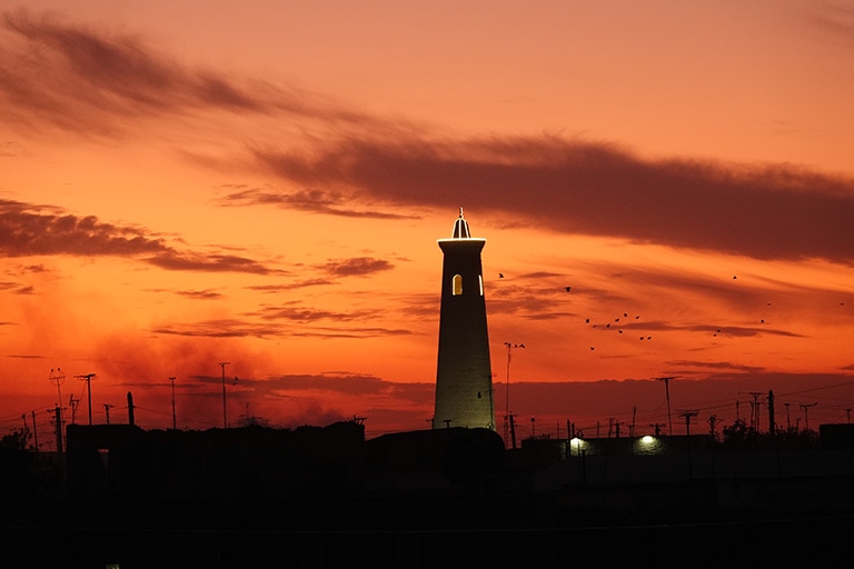 Things to do in Khiva - Sunset views from the old city walls of a minaret silhouetted against an orange sky 