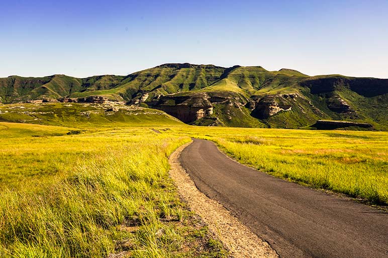 Single lane road in South Africa - road surrounded by green mountains