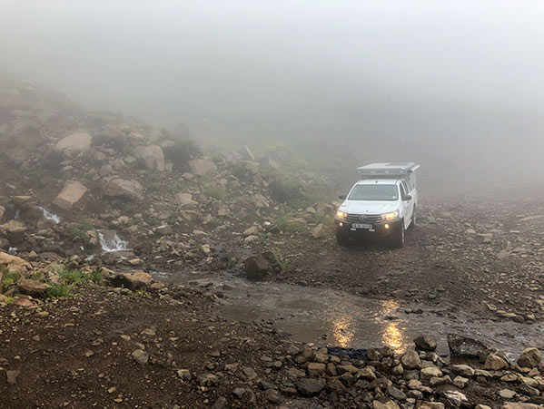 4x4 descending a foggy and rocky single lane road