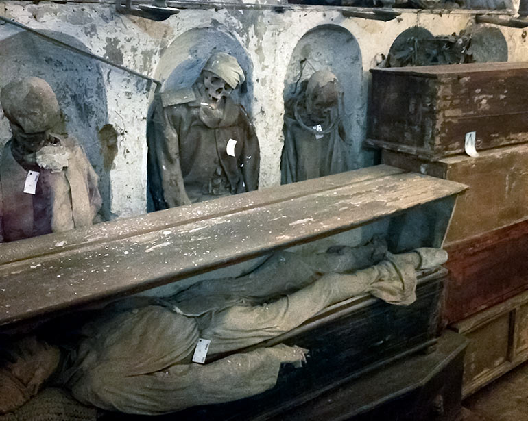 Palermo Catacombs with corpses stood in arches and some laid horizontally in wooden boxes