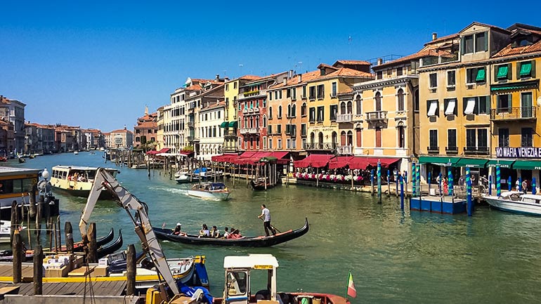 Venice canal and colourful houses on the canal with a gondola on the river