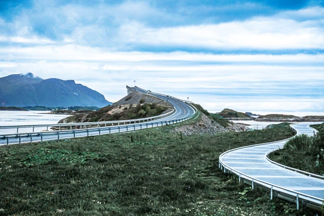 winding road and walking path under a cloudy, moody sky beside the sea