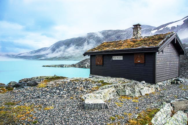 old wooden hut on a green watered lake