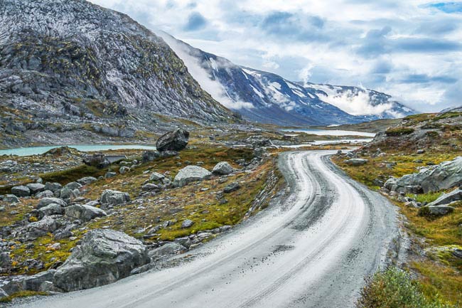 gravel road amongst snowy mountains