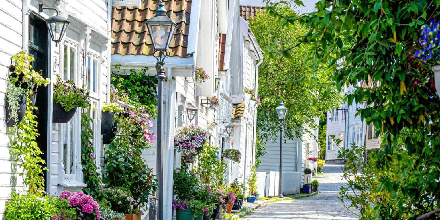 Norway road trip Header White timber houses with flowers in pots and hanging baskets