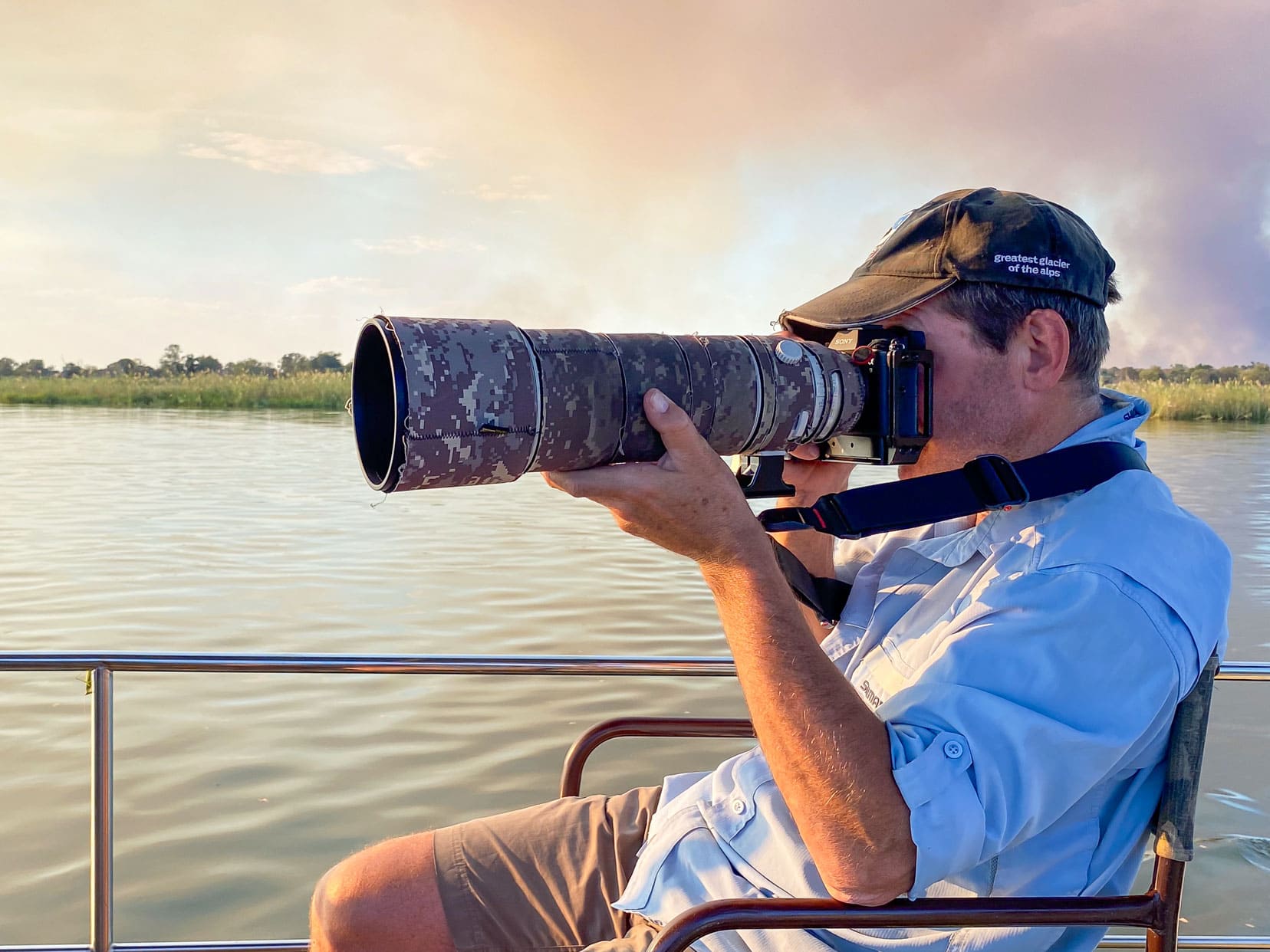 man holding a camera and long lens on a boat 
