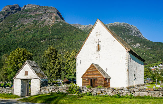 Kinsarvik Church white stone church with green mountain background