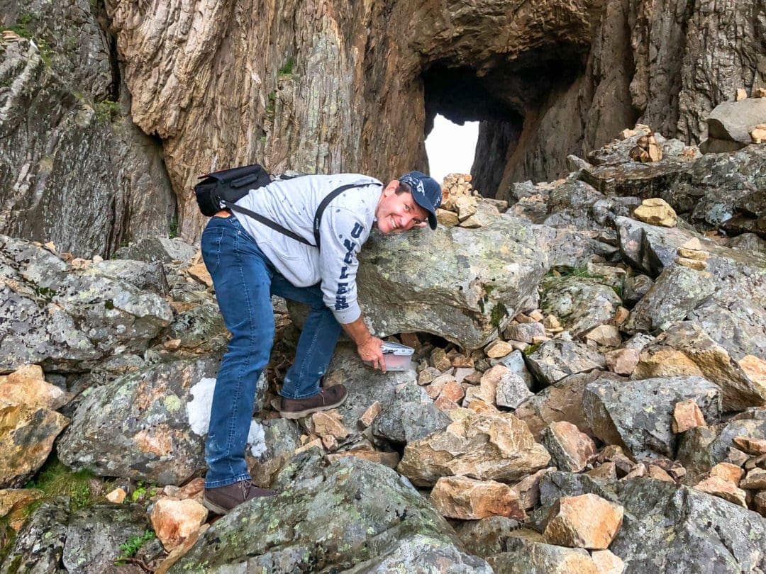 man finding a plastic container underneath a rock