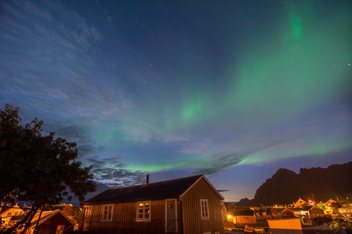 Green Northern Lights over a traditional Norwegian wooden housed village