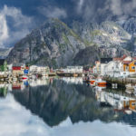 village with a mountain reflection in the water in front