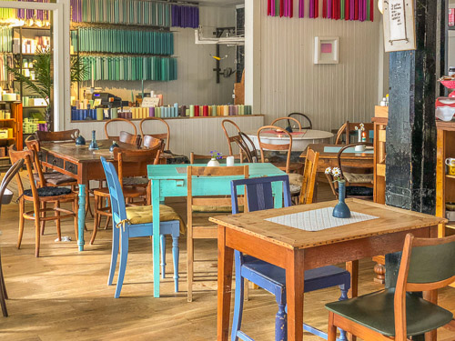 cafe interior has soft coloured furniture and wall hangings