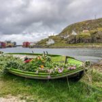Green boat with flowers in it beside the sea 