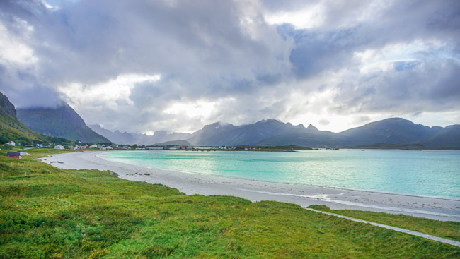 white sandy beach surrounded by mountains with an aqua sea