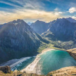 Looking on a white beach under a steep sided mountain