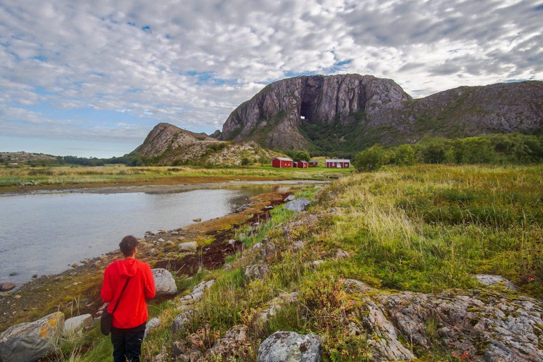 lady looking at a hole in a mountain across the water