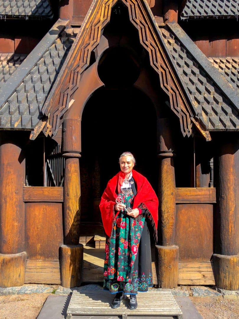 lady in traditional norwegian dress outside a stave church