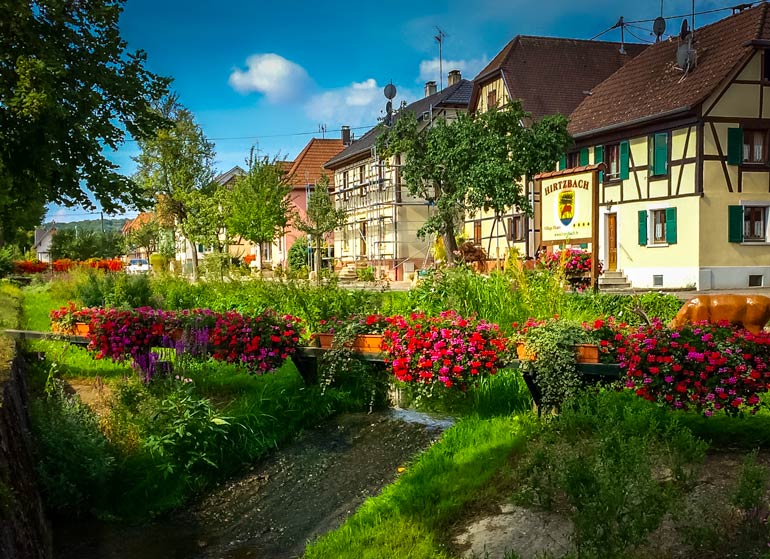 Hirtzbach timbered houses beside a flower lined river
