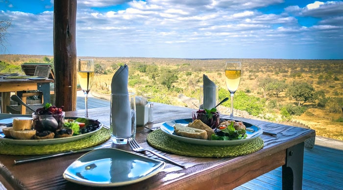 Lunch-at-Misava - view of table with plate of food and bushveld in the background