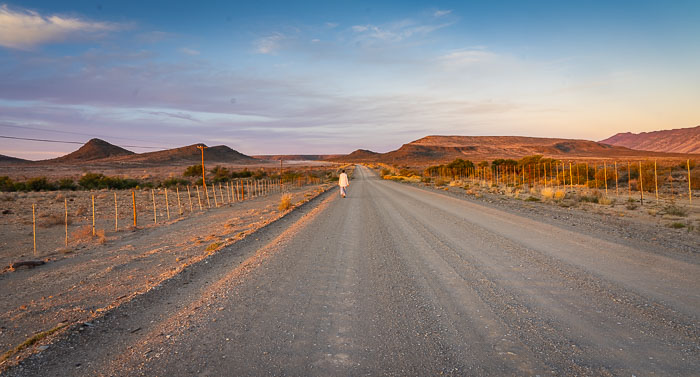 Woman walking along the road towards mountains 