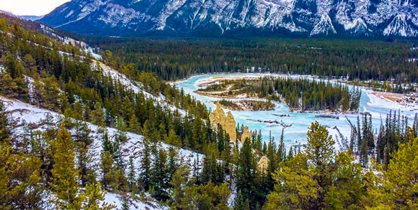 Banff-Hoodoos-in-Banff-National-Park limestone pillars in amongst trees and a lake in the background