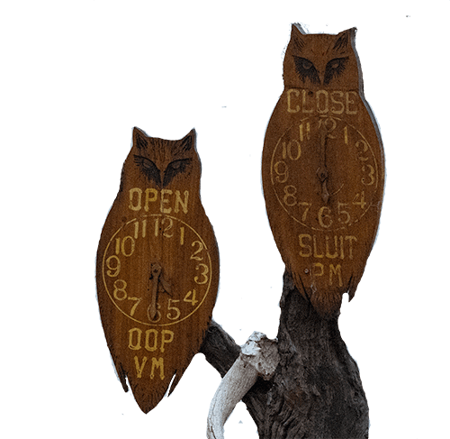 two wooden owls with clock hands showing Kruger rest camp open and closed times