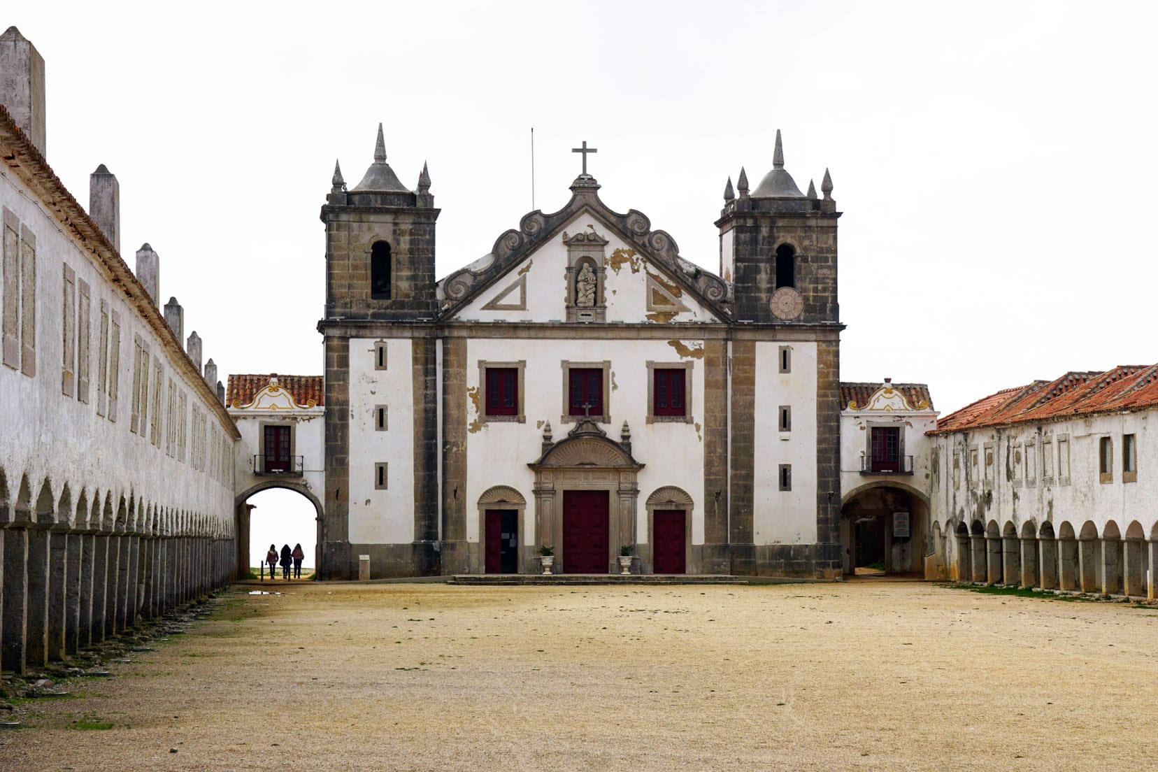 Nossa-Senhorado-Cabo-Church - a white church with red rimmed windows and doors and two long buildings attached
