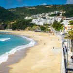 Sesimbra-beach-portugal - long stretch of beach with trees and houses in the background