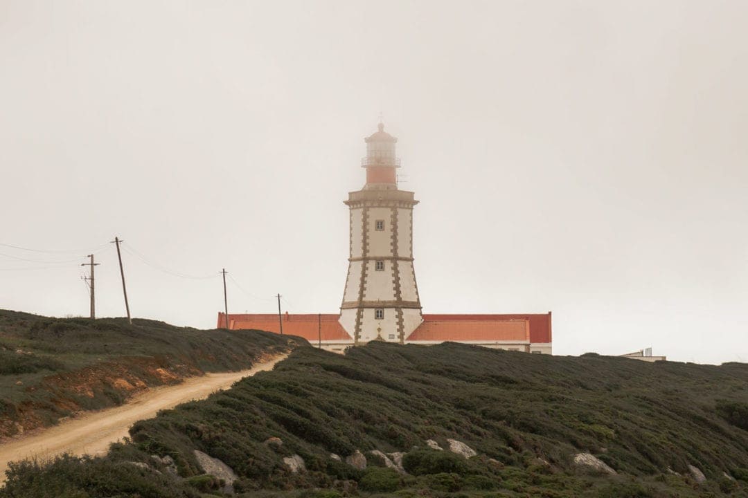 long lighthouse on a hill in fog